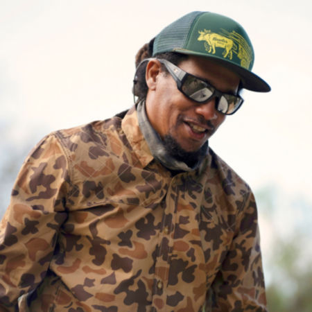 A man wearing the '71 camo shirt and a green, flat-brimmed hat
