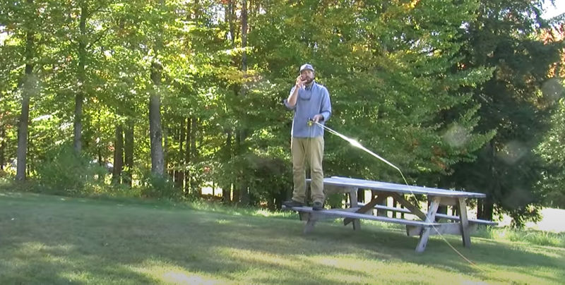An instructor holding a fishing rod while standing on a picnic bench