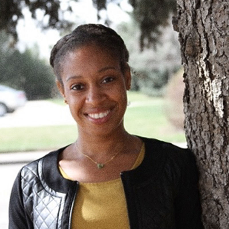 A headshot of Dr. Sparkle Malone leaning against a tree