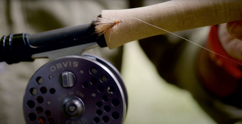 A close up image of fly rod and reel with fly.