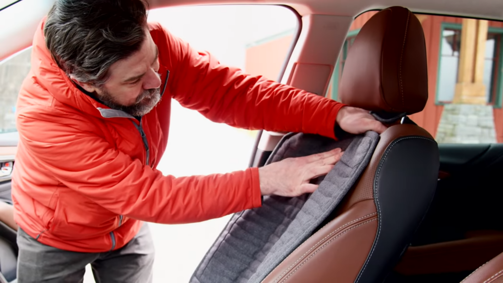 A man installing an Orvis Grip-Tight® Backseat Protector.