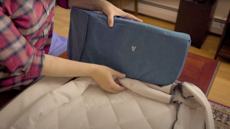 A close up on a woman's hands assembling the cover of a RecoveryZone lounger dog bed.