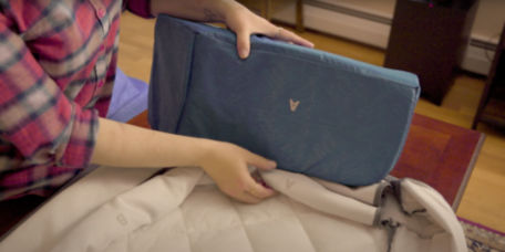 A close up on a woman's hands assembling the cover of a RecoveryZone lounger dog bed.