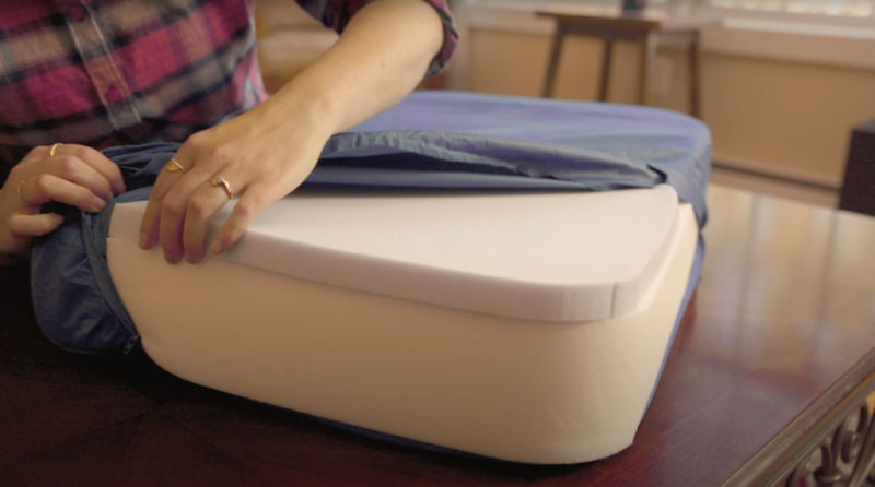 A woman wearing flannel assembling a lounger dog bed..
