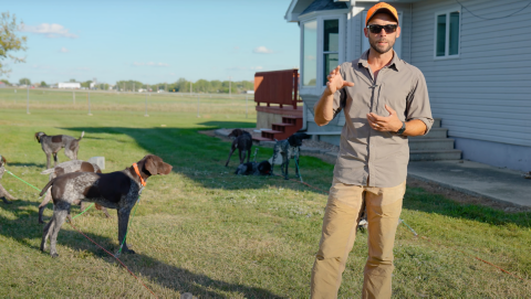 Ethan standing in a lawn with many dogs