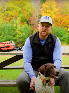 A man sitting at a picnic table with his dog