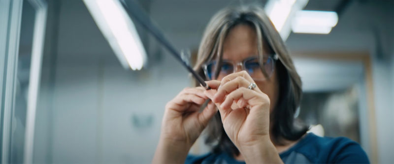 A close-up of a worker's hands as they inspect a fly rod