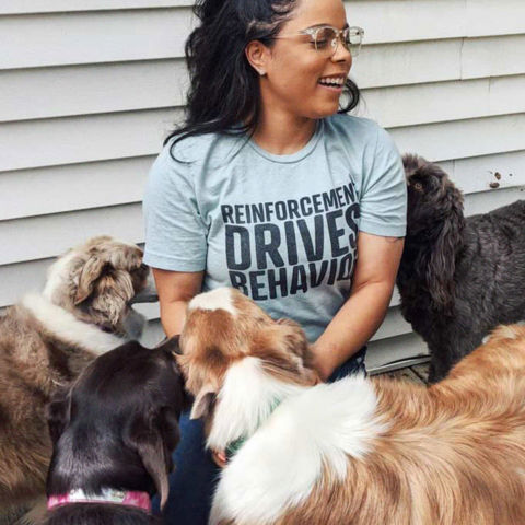 Melinda wearing a gray shirt surrounded by dogs