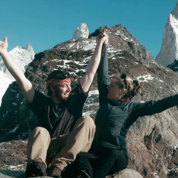 A mother and son with arms raised in celebration on top of a mountain.