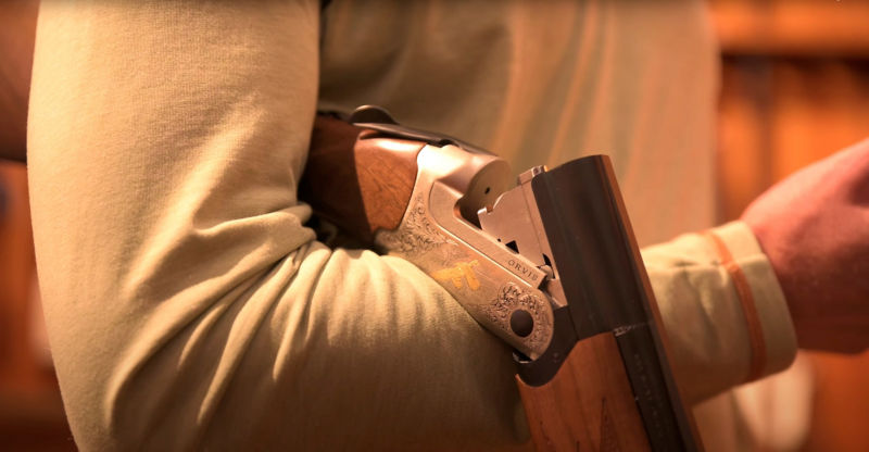 A close up of a shotgun being held correctly over an arm