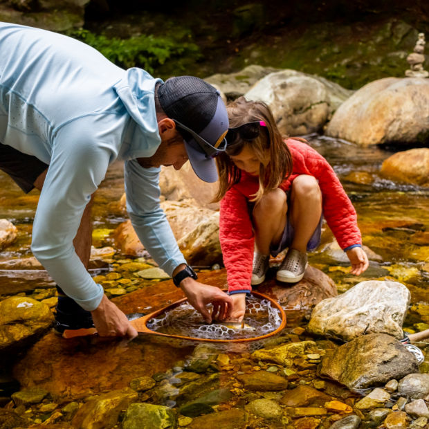 Simon Perkins and his small daughter release a small fish back into a rocky stream.