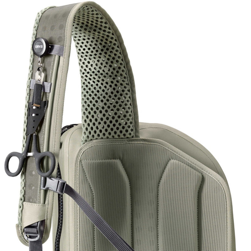 The strap of a fishing pack with several small tools attached