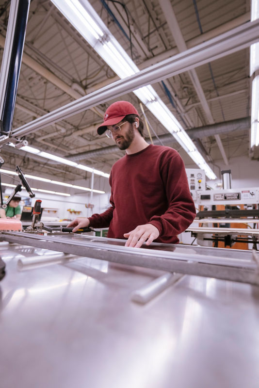 A rod shop worker adjusts a piece of equipment in the making of a rod.