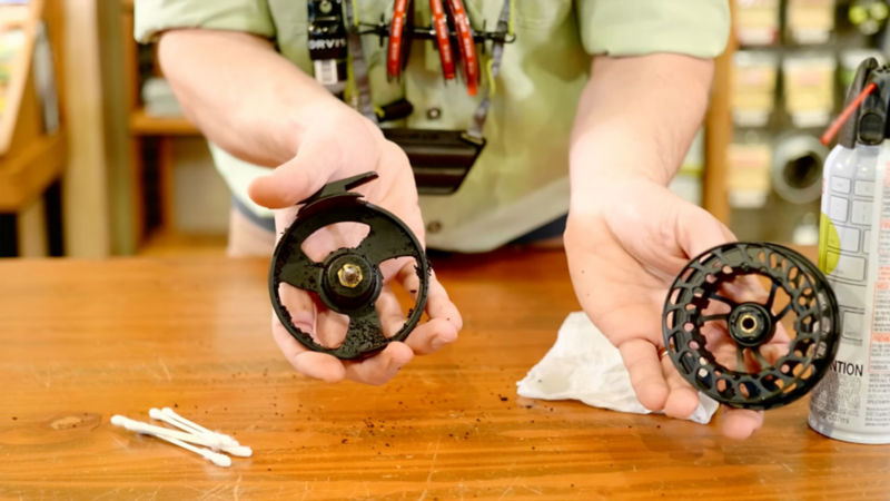 Two hands holding a disassembled fly reel.