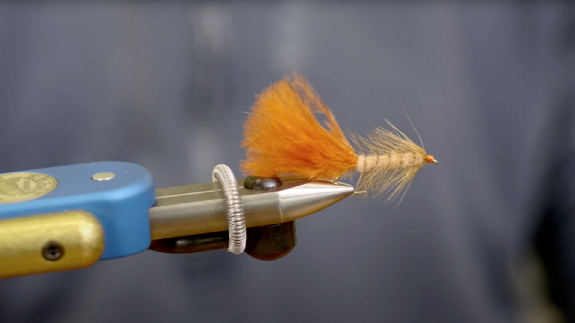 A close up of a fly-fishing fly held in pliers