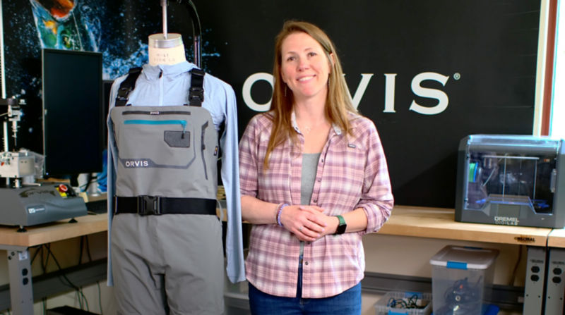 An Orvis designer stands next to a mannequin wearing a pair of waders.